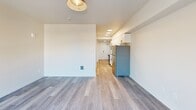 Located on Martin Luther King Jr Way S in Seattle's Rainier Valley neighborhood, this thoughtfully designed one-bedroom, one-bathroom unit offers a bright and modern living experience across a single floor. Light wood-style plank flooring runs throughout, tying the spaces together with a clean, contemporary aesthetic.

The open-concept living, dining, and kitchen area forms the heart of the unit. The galley-style kitchen is well-appointed with white shaker cabinetry featuring matte black hardware, white quartz countertops, a stainless steel sink, and a full suite of stainless steel appliances including a refrigerator, electric range, over-the-range microwave, and dishwasher. Recessed circular ceiling lights illuminate the kitchen corridor, leading toward the living area.

The living space is filled with natural light, thanks to a glass-paneled entry door and large windows that offer views of the surrounding neighborhood. The bedroom provides a comfortable and private retreat, complemented by a dedicated closet for storage.

The bathroom is finished with wood-look flooring, a white vanity with ample drawer storage, matte black fixtures, a tub-shower combination with white tile surround, and warm sconce lighting, creating a clean and functional space. The overall design balances modern finishes with practical, efficient use of space.