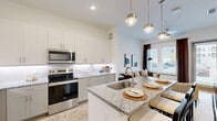 Located in Fort Worth, Texas, this thoughtfully designed one-bedroom, one-bathroom residence offers a cohesive open-concept layout finished with light hardwood flooring and crisp white walls throughout. The combined kitchen and living area forms the heart of the home, where a generous granite-topped island with an undermount sink and pendant lighting serves as both a functional workspace and casual dining spot. The kitchen is outfitted with stainless steel appliances, including a refrigerator with ice and water dispenser, an electric range, and a built-in microwave, all complemented by floor-to-ceiling white shaker cabinetry. The living room receives abundant natural light through large windows dressed with elegant brown drape panels, with direct access to an outdoor area. The bedroom is a calm retreat featuring dual windows with outdoor views, providing excellent natural light. The full bathroom is finished with a granite-topped vanity, a glass-enclosed shower with marble-style tile, and direct access to a generously sized walk-in closet. The walk-in closet features built-in shelving and multiple hanging rods, offering exceptional storage and organization capacity for a residence of this scale.