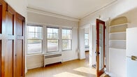 Located in Milwaukee's vibrant East Side neighborhood, this 2-bedroom, 1-bathroom unit at 1505 North Franklin Place blends classic architectural character with functional living. Throughout the space, light wood flooring and crisp white walls create a clean, consistent aesthetic, while traditional crown molding adds a timeless architectural detail to each room.

The primary bedroom is generously proportioned and features a bank of multi-pane double-hung windows that flood the room with natural light and frame views of the surrounding Milwaukee cityscape. A set of rich, dark-stained wooden bi-fold closet doors provides both storage and a warm contrast to the bright walls. A classic brass flush-mount ceiling fixture completes the room. Radiant heating units beneath the windows ensure comfort year-round.

The second bedroom is more intimate in scale, also featuring a multi-pane window with city views and its own radiator unit. The compact kitchen is efficiently laid out with white cabinetry, a gas range, and a full-size refrigerator. The bathroom retains its vintage character with classic white subway tile surrounding a bathtub with overhead shower, a pedestal sink, and original mosaic penny tile flooring. Rich, dark-wood panel doors are found throughout, adding warmth and historic charm to the entire unit.