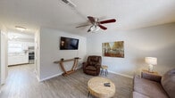 This two-story home offers a well-organized layout with two bedrooms, two bathrooms, and a thoughtful distribution of living space across both floors. The main level hosts the combined kitchen and living area, a hallway, a utility room, and staircase access to the upper floor.

The living room features light wood-style flooring, neutral painted walls, a textured ceiling, and a ceiling fan with a light fixture. A wall-mounted TV, natural light from a leaded glass window, and warm, casual furnishings create a comfortable and inviting atmosphere.

The kitchen is equipped with white cabinetry, light countertops, a stainless steel range, dishwasher, and built-in microwave. A window above the sink allows natural light into the space, complemented by track lighting overhead.

The upper floor contains both bedrooms and two full bathrooms. The spacious primary bedroom features plush carpeting, a ceiling fan, a natural light window with decorative leaded glass, and ample room for a full furniture arrangement. The second bedroom is cozy with carpeted flooring, a ceiling fan, and a window offering natural light. One bathroom features a tub-shower combo with wood-style flooring, while the second bathroom includes a vanity with light countertops. A staircase connects the two floors efficiently.