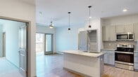 Located at 1001 Sundial Dr in Sneads Ferry, NC, this single-story, three-bedroom, two-bathroom home offers a thoughtfully designed layout with modern finishes throughout. The open-concept living and kitchen area serves as the heart of the home, where light hardwood-style flooring, recessed lighting, and pendant lights over a central island create a contemporary atmosphere. The kitchen is well-appointed with granite countertops, a geometric tile backsplash, shaker-style cabinetry, stainless steel appliances, and a ceiling fan in the adjacent living area. A door leads to an outdoor balcony, bringing in natural light and providing outdoor access. The two bathrooms continue the refined aesthetic with granite-topped vanities, hardwood-style flooring, and a tiled tub-shower combination. Each bedroom features plush carpeting, ceiling fans, and windows that invite natural light. Three closets—including generously sized walk-in closets with wire shelving systems—provide ample storage. A dedicated laundry room with full-size washer and dryer adds everyday convenience. The home's clean, neutral palette and consistent use of quality materials create a cohesive and functional living environment throughout.