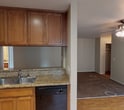 Located at 523 Broadway in El Cajon, this single-story unit offers a practical and comfortable layout with a cohesive design throughout. The living area features a combination of wood-look hard flooring and plush carpet, with a ceiling fan overhead and sliding glass doors that open to a private outdoor balcony, allowing natural light to fill the space. The open layout connects the living area directly to the kitchen, which is well-equipped with warm wood cabinetry extending to the ceiling, granite-style countertops, a stainless steel refrigerator, stainless microwave, and a black electric range. A double stainless steel sink and a window overlooking the exterior complete the kitchen. The bedroom is carpeted and features a ceiling fan with light, a walk-in closet, and a window with outdoor views, creating a bright and airy feel. The bathroom includes a wood-toned vanity with granite-style countertop, a large mirror with overhead lighting, and a full tub and shower combination. Neutral wall tones and consistent finishes throughout give the unit a clean, move-in-ready ambiance.