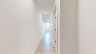 This well-designed one-bedroom, one-bathroom unit in Everett, MA offers a thoughtfully laid-out living space with a clean, modern aesthetic. Light hardwood flooring runs throughout, complementing the crisp white walls and creating a bright, cohesive atmosphere.

The open-concept kitchen and living area serves as the heart of the unit. The kitchen is outfitted with two-tone cabinetry — sleek white upper cabinets paired with warm wood-toned lower cabinets — set against white quartz countertops. A full suite of stainless steel appliances, including a French door refrigerator, range, microwave, and dishwasher, provide a polished, contemporary finish. Recessed lighting illuminates the space, and a wall-mounted mini-split unit ensures year-round climate comfort.

The living area benefits from an abundance of natural light, courtesy of multiple large double-hung windows that frame views of the surrounding Everett neighborhood and lush treetops, enhancing the airy feel of the space.

The bathroom continues the modern design language with a wood-toned vanity topped with a white countertop, a large mirror, and clean white tile flooring. A convenient hallway connects the living spaces, completing the efficient and functional floor plan of this contemporary unit.