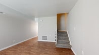 Located at 1951 Milton Rd in Charlotte, NC, this two-floor home offers a practical and well-organized layout across its two levels. The main floor features warm hardwood-style flooring throughout the open living areas, creating a cohesive and inviting atmosphere. A carpeted staircase with a decorative white metal railing connects the two floors, serving as a central architectural element of the home.

The kitchen is equipped with white shaker-style cabinetry, granite-look countertops, a subway tile backsplash, and black appliances including a range and a full-size refrigerator, all set over hardwood-style flooring. The bathroom is finished with a white vanity, a tiled shower-tub combination, and hardwood-style flooring, presenting a clean and functional design.

The upper level continues with carpeted bedrooms that offer a quieter, comfortable feel. One bedroom features a window with blinds that allows natural light to fill the room. Neutral gray and beige tones are carried throughout the home, lending a consistent and understated aesthetic. HVAC vents are integrated throughout both floors, ensuring climate control. The overall layout is straightforward and functional, making this Charlotte home a well-structured space suited for everyday living.