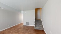 Located at 1951 Milton Rd in Charlotte, NC, this two-floor home offers a practical and well-organized layout across its two levels. The main floor features warm hardwood-style flooring throughout the open living areas, creating a cohesive and inviting atmosphere. A carpeted staircase with a decorative white metal railing connects the two floors, serving as a central architectural element of the home.

The kitchen is equipped with white shaker-style cabinetry, granite-look countertops, a subway tile backsplash, and black appliances including a range and a full-size refrigerator, all set over hardwood-style flooring. The bathroom is finished with a white vanity, a tiled shower-tub combination, and hardwood-style flooring, presenting a clean and functional design.

The upper level continues with carpeted bedrooms that offer a quieter, comfortable feel. One bedroom features a window with blinds that allows natural light to fill the room. Neutral gray and beige tones are carried throughout the home, lending a consistent and understated aesthetic. HVAC vents are integrated throughout both floors, ensuring climate control. The overall layout is straightforward and functional, making this Charlotte home a well-structured space suited for everyday living.