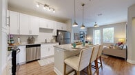 This thoughtfully designed 2-bedroom, 2-bathroom residence offers a functional and stylish single-floor layout. The open-concept kitchen and living area serves as the heart of the home, featuring white shaker cabinetry, subway tile backsplash, granite countertops, and a full suite of stainless steel appliances. A central island with seating provides an ideal space for casual dining, while pendant and track lighting add a polished finish. The living room flows naturally from the kitchen and is brightened by a glass door that opens to a private balcony, complemented by a ceiling fan overhead. Both bedrooms are carpeted and comfortably sized, with the primary bedroom featuring natural light from multiple windows and a ceiling fan. Each bedroom is served by its own closet, including a spacious walk-in fitted with wire shelving systems offering generous storage capacity. The two bathrooms are well-finished, with the primary bath showcasing a dual-sink granite vanity, white cabinetry, and a subway-tiled soaking tub. A dedicated in-unit laundry room accommodates a full-size washer and dryer. Throughout the home, wood-look flooring in the main living areas and neutral tones create a cohesive, inviting ambiance.