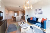 Located at 8450 N Belt Line Rd in Irving, Texas, this single-floor residence showcases a thoughtfully designed open-concept layout with contemporary finishes throughout. The living area is anchored by a striking cluster pendant light fixture with amber glass globes, light wood-tone flooring, and a sliding glass door that opens to a private balcony offering expansive panoramic views of the Irving skyline. Recessed lighting complements the warm, inviting ambiance of the space.

The kitchen is a standout feature, equipped with flat-front wood-grain cabinetry, white quartz countertops, a textured dark tile backsplash, and a full suite of stainless steel appliances including a French door refrigerator, gas range, and built-in microwave. A center island with bar seating provides additional workspace and a natural gathering point between the kitchen and living area.

The bedrooms are bright and comfortable, each featuring large windows that frame sweeping outdoor views and ceiling fans for added comfort. The bathroom is finished with a wood-grain vanity, white quartz countertop, glass-enclosed soaking tub and shower combination, and open built-in shelving, creating a clean, spa-like atmosphere throughout.
