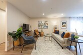 Located at 665 Talbot St in London, Ontario, this two-bedroom, two-bathroom residence offers a thoughtfully designed single-floor layout that maximizes comfort and functionality. Light-toned hardwood-style flooring flows throughout the main living areas, creating a cohesive and inviting ambiance.

The open-concept living and dining area is bright and welcoming, with recessed lighting and large windows that allow generous natural light to fill the space. The kitchen features crisp white shaker-style cabinetry, white countertops, and stainless steel appliances including a range with over-the-range microwave and a full-size refrigerator. A breakfast bar provides additional seating and connects the kitchen seamlessly to the dining area.

The primary bedroom is generously proportioned, offering a large sliding-door closet and a serene atmosphere with soft carpet underfoot. A corner window brings in natural light and a view of the surroundings. The second bedroom is similarly well-sized with ample closet storage.

Both bathrooms are finished in clean, neutral tones. One features a soaker tub with tiled surround, while the other includes a vanity with white cabinetry and hardwood-style flooring. In-unit laundry adds everyday convenience, completing this practical and stylish urban residence.