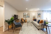 Located at 665 Talbot St in London, Ontario, this two-bedroom, two-bathroom residence offers a thoughtfully designed single-floor layout that maximizes comfort and functionality. Light-toned hardwood-style flooring flows throughout the main living areas, creating a cohesive and inviting ambiance.

The open-concept living and dining area is bright and welcoming, with recessed lighting and large windows that allow generous natural light to fill the space. The kitchen features crisp white shaker-style cabinetry, white countertops, and stainless steel appliances including a range with over-the-range microwave and a full-size refrigerator. A breakfast bar provides additional seating and connects the kitchen seamlessly to the dining area.

The primary bedroom is generously proportioned, offering a large sliding-door closet and a serene atmosphere with soft carpet underfoot. A corner window brings in natural light and a view of the surroundings. The second bedroom is similarly well-sized with ample closet storage.

Both bathrooms are finished in clean, neutral tones. One features a soaker tub with tiled surround, while the other includes a vanity with white cabinetry and hardwood-style flooring. In-unit laundry adds everyday convenience, completing this practical and stylish urban residence.