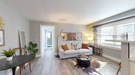 Located at 503 W 46th St in Kansas City, MO, this thoughtfully designed one-bedroom, one-bathroom unit offers a well-organized layout across a single floor. Light gray walls and durable wood-look flooring run throughout, creating a cohesive, contemporary aesthetic.

The combined kitchen and living area forms the heart of the unit. The living space is bright and welcoming, with large windows dressed in patterned curtains that allow natural light to fill the room. A woven pendant light and modern coffee table add character to the area. Adjacent to the living space is a compact dining nook with a bistro-style table and bentwood chairs. The kitchen is efficiently appointed with white shaker cabinetry, light quartz countertops, a subway tile backsplash, and a full suite of stainless steel appliances including a gas range, refrigerator, microwave, and dishwasher.

The bedroom is a calm and comfortable retreat, featuring corner windows, a ceiling fan, and a closet with louvered bifold doors. The bathroom stands out with a striking walk-in glass shower clad in bold blue-and-white marbled wall panels, complemented by a white vanity and classic hexagonal tile flooring. A connecting hallway ties all rooms together efficiently, completing this well-appointed unit.