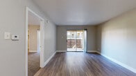 This well-appointed one-bedroom, one-bathroom unit offers a thoughtfully designed layout across a single floor, making efficient use of its compact footprint. The living room is a bright, welcoming space finished with durable hardwood-style flooring and neutral gray walls. A sliding glass door floods the room with natural light and opens to a private balcony with outdoor views, creating a seamless indoor-outdoor connection. Vertical blinds provide privacy and light control.

The kitchen is fitted with stainless steel appliances, including a full-size refrigerator and electric range, complemented by gray cabinetry, light countertops, and a classic white subway tile backsplash. Light-toned flooring keeps the space feeling clean and bright.

The bedroom is a comfortable retreat featuring plush wall-to-wall carpeting, a ceiling fan with lighting, and its own sliding door access. A dedicated walk-in closet with built-in shelving and hanging space provides generous storage. The bathroom includes a vanity with an undermount sink, gray cabinetry, and a tiled shower-tub combination. Throughout the unit, clean white trim and a consistent neutral color palette contribute to a cohesive, move-in-ready aesthetic.