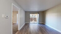 This well-appointed one-bedroom, one-bathroom unit offers a thoughtfully designed layout across a single floor, making efficient use of its compact footprint. The living room is a bright, welcoming space finished with durable hardwood-style flooring and neutral gray walls. A sliding glass door floods the room with natural light and opens to a private balcony with outdoor views, creating a seamless indoor-outdoor connection. Vertical blinds provide privacy and light control.

The kitchen is fitted with stainless steel appliances, including a full-size refrigerator and electric range, complemented by gray cabinetry, light countertops, and a classic white subway tile backsplash. Light-toned flooring keeps the space feeling clean and bright.

The bedroom is a comfortable retreat featuring plush wall-to-wall carpeting, a ceiling fan with lighting, and its own sliding door access. A dedicated walk-in closet with built-in shelving and hanging space provides generous storage. The bathroom includes a vanity with an undermount sink, gray cabinetry, and a tiled shower-tub combination. Throughout the unit, clean white trim and a consistent neutral color palette contribute to a cohesive, move-in-ready aesthetic.