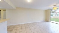 Located at 750 NW 8th St in Florida City, FL, this three-bedroom, two-bathroom single-floor residence offers a practical and well-organized layout. Light-toned ceramic tile flooring runs throughout the entire home, creating a clean, cohesive look. The open-concept kitchen and living area forms the heart of the space, where a peninsula with a built-in sink and light countertop provides both prep space and a natural divider. The kitchen features dark cabinetry contrasted by white appliances, including a range, microwave, refrigerator, and dishwasher, complemented by a beige tile backsplash. The living area extends toward a full-length sliding glass door that fills the space with natural light and opens to a view of lush tropical greenery. Each bedroom is equipped with a ceiling fan and window, with the primary bedroom offering a comfortable footprint. Both bathrooms are finished with matching beige tile surrounds in the tub-shower combinations, vanity mirrors, and neutral countertops, lending a consistent and clean aesthetic. A dedicated hallway connects the rooms efficiently, and a closet provides additional storage. The overall ambiance is bright, airy, and low-maintenance—well-suited for the warm South Florida climate.