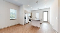 Located on Parlor Street in Venice, Florida, this single-floor unit showcases a clean, contemporary design with a bright, open layout. Light wood-style flooring runs consistently throughout every room, contributing to a cohesive and airy aesthetic.

The kitchen serves as a central focal point, designed with an open-concept layout that connects seamlessly to the living areas. Light-toned cabinetry extending to the ceiling provides generous storage, while stainless steel appliances—including a French door refrigerator with ice dispenser, electric range, and built-in microwave—offer modern functionality. A large center island with a quartz-style countertop and undermount sink doubles as a prep area and casual dining space.

The living area is well-lit by multiple windows fitted with horizontal blinds, allowing natural light to fill the space. The entry features recessed lighting and a secure front door. Bedrooms are comfortably sized, each with windows that bring in natural light and views of the surrounding greenery.

The bathroom includes a full tub-shower combination with tiled surround, complemented by light wood-grain cabinetry with matte black hardware and clean white walls. Throughout the unit, the design prioritizes simplicity, functionality, and a bright, neutral palette.