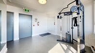Located at 1 Chapel St in Nanaimo, BC, this dedicated fitness facility offers a well-equipped exercise space designed to support a well-rounded workout routine. The room is finished with clean white walls, a durable speckled grey floor, and a textured ceiling, creating a bright and functional environment throughout.

Large windows line one side of the space, flooding the interior with natural light and framing impressive views of the surrounding waterfront and landscape — a standout feature that elevates the workout experience. Full-length mirrors are strategically placed to enhance the sense of openness and provide visual feedback during exercise.

The facility is equipped with a selection of modern cardio machines, including Matrix treadmills, an elliptical trainer, and a stationary bike, all positioned to take advantage of the scenic views. A dedicated free weights area features a multi-tier dumbbell rack and an adjustable weight bench, while a cable machine supports a variety of strength training movements. Rubber floor mats are placed in key workout zones to provide grip and protection.

Climate control is handled by a wall-mounted air conditioning unit, ensuring comfort year-round. The space also includes fire safety equipment and clearly marked emergency exits. Motivational wall decals add an energetic touch, making this fitness room a practical and inspiring place to train.