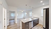Located at 25100 Ashton Cir in Frankford, Delaware, this efficiently designed one-bedroom, one-bathroom residence offers a thoughtfully arranged single-floor layout. The open-concept kitchen and living area serves as the heart of the home, where a large granite-topped island with a built-in sink and pendant lighting creates a natural focal point. Dark espresso cabinetry contrasts elegantly with the light granite countertops, while a full suite of stainless steel appliances—including a refrigerator, range, and microwave—adds a modern, functional touch. Recessed and pendant lighting illuminate the kitchen, which flows seamlessly into the living area, where a ceiling fan and natural light from window blinds contribute to a bright, airy atmosphere. Wood-look flooring runs consistently throughout the entire residence, lending warmth and visual continuity. The bedroom is a comfortable, well-proportioned space featuring multiple windows that invite natural light, a ceiling fan, and access to a full bathroom. The bathroom is cleanly appointed with matching dark cabinetry, a granite vanity top, and a walk-in shower. Two closets and a dedicated laundry area provide practical storage and utility solutions, rounding out this well-organized home.