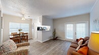 This 1-bedroom, 1-bathroom residence is thoughtfully laid out across a single floor, maximizing every square foot for practical, comfortable living. The living room serves as the heart of the home, featuring wood-style plank flooring, crown molding, and a set of French doors that invite natural light and provide outdoor access, creating a bright and welcoming atmosphere.

Adjacent to the living room, the combined dining and kitchen area offers a seamless flow ideal for everyday living and entertaining. The dining nook is framed by a large window with outdoor views and is accented by a ceiling fan overhead. The kitchen features a pass-through counter, white cabinetry, speckled countertops, and a window above the workspace, keeping the area bright and functional.

The bedroom is a comfortable retreat with plush carpeting, crown molding, a large window with natural light and greenery views, and a closet for ample storage. The neutral color palette lends a calm and restful ambiance.

The bathroom is well-appointed with a tub-shower combination, a single vanity with a large mirror, and classic white finishes. Consistent with the rest of the home, neutral tones and clean design keep the space feeling fresh and organized throughout.