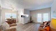 This 1-bedroom, 1-bathroom residence is thoughtfully laid out across a single floor, maximizing every square foot for practical, comfortable living. The living room serves as the heart of the home, featuring wood-style plank flooring, crown molding, and a set of French doors that invite natural light and provide outdoor access, creating a bright and welcoming atmosphere.

Adjacent to the living room, the combined dining and kitchen area offers a seamless flow ideal for everyday living and entertaining. The dining nook is framed by a large window with outdoor views and is accented by a ceiling fan overhead. The kitchen features a pass-through counter, white cabinetry, speckled countertops, and a window above the workspace, keeping the area bright and functional.

The bedroom is a comfortable retreat with plush carpeting, crown molding, a large window with natural light and greenery views, and a closet for ample storage. The neutral color palette lends a calm and restful ambiance.

The bathroom is well-appointed with a tub-shower combination, a single vanity with a large mirror, and classic white finishes. Consistent with the rest of the home, neutral tones and clean design keep the space feeling fresh and organized throughout.