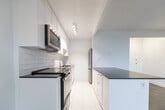Located at 95 Gamble Ave in Toronto's East York neighbourhood, this one-bedroom, one-bathroom unit offers a well-considered layout across a single floor. The combined kitchen and living area forms the heart of the home, where gleaming parquet flooring and large windows fill the space with natural light and sweeping city views. A door leads directly to a private balcony, extending the living area outdoors. The kitchen has been renovated to a modern standard, featuring white shaker-style cabinetry, dark countertops, stainless steel appliances including a built-in microwave and refrigerator, a subway tile backsplash, and bright porcelain tile flooring. A peninsula with additional counter space connects the kitchen to the living area, providing a functional transition between the two zones. The bedroom is a well-proportioned, quiet retreat with the same warm parquet flooring and clean white walls. The bathroom is finished with classic white subway tile surrounding a full soaker tub and shower combination, paired with chrome fixtures for a crisp, timeless look. A dedicated entrance and hallway complete this efficiently designed home.