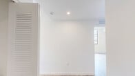 Located at 2585 Spruce Ave in West Palm Beach, FL, this modern single-story home offers a clean, contemporary design across four bedrooms and two bathrooms. The open-concept kitchen and living area serves as the heart of the home, showcasing floor-to-ceiling white cabinetry, a large waterfall-edge island, stainless steel appliances including a range, microwave, dishwasher, and refrigerator, and a bright window that fills the space with natural light. Light-toned wood flooring runs throughout, complementing the crisp white walls and creating a cohesive, airy ambiance. The living area features expansive floor-to-ceiling sliding glass doors that open to a private balcony with vibrant greenery views and additional windows that flood the space with Florida sunshine. Each of the four bedrooms is well-proportioned, with large windows, ceiling fans, and ample closet space, including walk-in closets in select rooms. The two bathrooms are finished in a clean modern style — one with a frameless glass walk-in shower and another with a full soaking tub and shower combo, both featuring white vanities with under-mount sinks and large mirrors. The hallway connects all rooms efficiently, making the layout feel functional and well-organized throughout.
