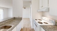 Located at 20939 Parthenia St in Canoga Park, CA, this single-story unit offers a thoughtfully arranged floor plan encompassing one bedroom, one bathroom, a kitchen, and a dedicated closet. The overall layout is compact yet functional, making efficient use of its available space.

The galley-style kitchen features granite-look countertops, white cabinetry with ample upper and lower storage, a stainless steel double sink, a refrigerator, and an electric range with hood ventilation. Wood-look flooring adds warmth and durability to the kitchen area.

The living area connects directly to the kitchen and is finished with neutral carpet and a ceiling fan, lending a comfortable, casual atmosphere. The bedroom is carpeted and receives natural light through a window fitted with vertical blinds. A textured ceiling is present throughout. A dedicated walk-in closet off the bedroom provides generous storage, featuring wrap-around hanging rods and carpeted flooring.

The bathroom includes a vanity with granite-look countertops, white cabinetry, a large mirror, a wall-mounted light fixture, and wood-look flooring, maintaining a clean and cohesive aesthetic consistent with the rest of the unit.