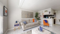 Located at 7222 Bellerive Dr in Houston, TX, this two-story home offers a thoughtfully designed layout spread across two well-proportioned floors. The main level welcomes you with a bright, open living room bathed in natural light from a large front-facing window. Light-toned tile flooring flows throughout, complementing the neutral gray walls and creating an airy, cohesive feel. The living area features a distinctive mirrored wall accent and a built-in shelving unit, adding both style and function. Adjacent to the living room, the kitchen is equipped with dark wood cabinetry, black appliances, a tile backsplash, and granite-style countertops, opening to a dedicated dining area. A laundry room and two closets add practical convenience on this level. A staircase with white railings leads to the upper floor, where the generously sized bedroom awaits. The bedroom features vaulted ceilings, a ceiling fan, an open loft-style railing overlook, and a closet. Two full bathrooms serve the home, each clean and well-appointed with tiled tub-shower combinations and wood-toned vanities. Throughout both levels, light flooring and soft neutral tones create a calm, inviting atmosphere ideal for comfortable everyday living.