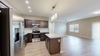This single-story home in Easley, SC offers a thoughtfully designed layout across three bedrooms and two bathrooms. The open-concept kitchen and living area serves as the heart of the home, featuring dark espresso cabinetry, granite countertops, a central island with pendant lighting overhead, and a full suite of stainless steel appliances including a French door refrigerator, range, microwave, and dishwasher. A subway tile backsplash adds a clean, contemporary touch, while light wood-tone flooring flows seamlessly throughout the main living areas.

The living room is generously sized, with a ceiling fan, neutral warm-toned walls, and sliding glass doors that allow natural light to pour in and provide outdoor access. The bedrooms feature plush carpet flooring and neutral walls; select rooms include windows with outdoor views of surrounding greenery. The primary bedroom offers a comfortable footprint with dedicated closet space.

The bathrooms are finished with granite-topped vanities and wood-toned cabinetry, and one includes a walk-in glass shower with chrome fixtures. A dedicated laundry room houses a full-size washer and dryer alongside the water heater. The overall aesthetic is clean, modern, and move-in ready.