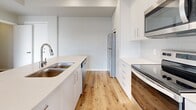 Located in Westbank in the heart of British Columbia's Central Okanagan, this well-designed two-bedroom, two-bathroom unit offers a bright and contemporary living experience. The open-concept main area seamlessly integrates the kitchen, dining, and living spaces, all finished with warm hardwood-style flooring that runs throughout. The kitchen is a standout feature, equipped with stainless steel appliances including a refrigerator, electric range, and built-in microwave, complemented by crisp white cabinetry extending to the ceiling, a subway tile backsplash, and a spacious island with a light quartz countertop and undermount sink. Large windows flood the living area with natural light and frame sweeping mountain views, which are also accessible from the private balcony. Both bedrooms are comfortably sized, featuring neutral grey walls, hardwood-style flooring, and windows that capture the scenic Okanagan landscape. The two bathrooms are finished in a clean, modern style with white fixtures and consistent flooring. Four closets, including a generous walk-in, provide ample storage throughout. An in-unit laundry area adds everyday convenience to this thoughtfully laid-out home in the Okanagan.