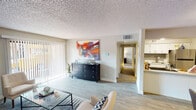 Located at 8560 W Peoria Ave in Peoria, Arizona, this single-floor residence offers a well-organized layout designed for functional and comfortable living. The open living room serves as the heart of the home, featuring light wood-look flooring, a textured ceiling, and large sliding glass doors lined with vertical blinds that open to a private patio, filling the space with natural light and providing outdoor access. The kitchen is appointed with crisp white cabinetry, light quartz-style countertops, a stainless steel sink and dishwasher, and a tasteful gray subway tile backsplash that adds a modern touch. A hallway connects the living and kitchen areas to the private quarters of the home. The primary bedroom is a calm retreat with plush carpeting, a window with blinds and curtains, and ample wall space. The second bedroom also features carpet flooring and a window, offering flexibility for various uses. The full bathroom is efficiently designed with wood-look flooring, a tub-shower combination, a white vanity with generous counter space, and a stacked washer and dryer unit conveniently integrated into the layout. Throughout the residence, neutral tones and consistent finishes create a cohesive and welcoming ambiance.
