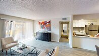 Located at 8560 W Peoria Ave in Peoria, Arizona, this single-floor residence offers a well-organized layout designed for functional and comfortable living. The open living room serves as the heart of the home, featuring light wood-look flooring, a textured ceiling, and large sliding glass doors lined with vertical blinds that open to a private patio, filling the space with natural light and providing outdoor access. The kitchen is appointed with crisp white cabinetry, light quartz-style countertops, a stainless steel sink and dishwasher, and a tasteful gray subway tile backsplash that adds a modern touch. A hallway connects the living and kitchen areas to the private quarters of the home. The primary bedroom is a calm retreat with plush carpeting, a window with blinds and curtains, and ample wall space. The second bedroom also features carpet flooring and a window, offering flexibility for various uses. The full bathroom is efficiently designed with wood-look flooring, a tub-shower combination, a white vanity with generous counter space, and a stacked washer and dryer unit conveniently integrated into the layout. Throughout the residence, neutral tones and consistent finishes create a cohesive and welcoming ambiance.
