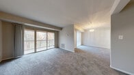 This well-laid-out 2-bedroom, 1-bathroom residence in Lanham, MD offers a comfortable and functional floor plan across a single level. The open-concept living and dining area is a standout feature, with plush carpeting underfoot and a wall of sliding glass doors that flood the space with natural light and provide direct access to a private balcony overlooking lush, tree-lined surroundings. A classic chandelier accents the dining area, adding a touch of elegance to the open layout.

The galley-style kitchen is efficiently designed with warm wood cabinetry, granite-look countertops, a stainless steel sink, and white appliances including a gas range, dishwasher, and refrigerator. Light ceramic tile flooring completes the practical and clean aesthetic of this space.

Both bedrooms are carpeted and offer generous proportions, with the primary bedroom providing ample room for furnishings. The primary bedroom also benefits from access to a dedicated walk-in closet with built-in shelving and hanging rods, offering excellent storage capacity. A second closet is also available in the unit.

The full bathroom features a tiled tub/shower combination with clean white fixtures. A connecting hallway ties the rooms together for a cohesive flow throughout the home.