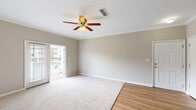 Located at 921 Timber Valley Way in Virginia Beach, Virginia, this single-floor residence offers a well-organized and comfortable layout with a neutral color palette throughout. The living area is a welcoming, open space featuring a combination of hardwood-style flooring and plush carpet, crown molding, and a ceiling fan with a light fixture. A glass door leads out to an outdoor deck, filling the room with natural light and providing access to exterior views. Adjacent to the living space, the kitchen is equipped with rich wood cabinetry, dark granite-style countertops, and black appliances including a refrigerator, gas range, and microwave. A convenient breakfast bar counter extends into the adjacent area, offering casual seating and additional workspace. The bedrooms are generously sized, finished with soft carpet and neutral walls, offering a calm and restful atmosphere with ample room for furnishings. Closet access is provided in the bedroom areas. The bathroom features a full tub-shower combination with white tile surround and clean, classic fixtures. Throughout the home, consistent crown molding, white six-panel doors, and warm-toned walls create a cohesive and polished interior aesthetic.