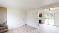 Located at 1224 W Breckenridge Dr in Mexico, Missouri, this two-story home offers three bedrooms, one bathroom, and a practical layout spread across two floors. The main level features light luxury vinyl plank flooring throughout the open living room and kitchen area, creating a bright and cohesive living space. Natural light flows in through windows overlooking the surrounding greenery. The galley-style kitchen is well-appointed with gray cabinetry, light stone-patterned countertops, a double-basin sink, and a full-size refrigerator. A glass door off the kitchen provides direct access to the backyard. Carpeted stairs lead to the upper floor, where all three bedrooms are located. Each bedroom features neutral carpet, light-toned walls, and windows that invite natural light. The primary bedroom includes a built-in closet with a hanging rod for convenient storage. The additional bedrooms offer comfortable, functional spaces with outdoor views. The full bathroom is equipped with a tub-shower combination. A hallway connects the upper-floor rooms, completing the efficient two-story layout. The home's clean, neutral palette and updated finishes provide a move-in ready environment throughout.