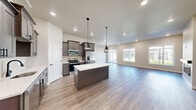 Located at 4411 Dacha Drive in Billings, Montana, this well-appointed two-story home offers 3 bedrooms, 4 bathrooms, and generous living space spread across two thoughtfully designed floors. The main floor hosts an expansive open-concept layout where the kitchen, dining, and living areas flow seamlessly together. The kitchen is a standout feature, showcasing rich dark-toned cabinetry, light quartz countertops, a subway tile backsplash, stainless steel appliances, a large center island with pendant lighting, and a dedicated pantry. The living area is bathed in natural light through large windows and includes a sleek fireplace, with light wood-look flooring extending throughout. A hallway with two-panel doors with matte black hardware leads to additional spaces on this level. The attached garage and a utility room add practical functionality. Upstairs, the second floor houses the bedrooms, including a spacious primary suite with its own bathroom featuring a walk-in shower, wood-tone vanity, and warm plank flooring. Additional bedrooms offer carpeted floors and ample closet space, with multiple walk-in and standard closets distributed throughout. Four full bathrooms and well-placed hallways ensure comfort and convenience across both levels.
