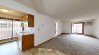 Located at 2052 15th St N in Saint Cloud, Minnesota, this single-floor, 3-bedroom, 1-bathroom unit offers a practical and comfortable layout. The open living area is generously sized, featuring neutral wall-to-wall carpeting, textured ceilings, and a sliding glass door that lets in natural light while providing outdoor access. Baseboard heating is present throughout, ensuring warmth during Minnesota winters.

The kitchen is efficiently designed with warm oak cabinetry, wood-toned countertops, tile flooring, and white appliances including a range and dishwasher. A pass-through opening connects the kitchen to the living area, creating a more open feel between the two spaces.

The spacious primary bedroom offers ample room and features carpeted flooring and baseboard heating. The two additional bedrooms are well-proportioned with carpet and clean white walls. Three closets are distributed throughout the unit, each outfitted with dual hanging rods and shelving for organized storage.

The full bathroom includes a single-sink oak vanity with a mirrored medicine cabinet, a tub/shower combination, and classic mosaic tile flooring. A hallway connects the bedrooms and bathroom, keeping the layout functional and straightforward. Overall, the unit presents a clean, no-frills living environment well-suited for everyday comfort.