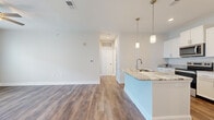 Located at 3788 Old Port Royal Rd N in Spring Hill, Tennessee, this well-appointed single-floor, one-bedroom, one-bathroom home offers a thoughtfully designed layout with modern finishes throughout. The open-concept living area features warm hardwood-style flooring and a ceiling fan, with French doors that invite natural light and provide outdoor views, creating a bright and welcoming atmosphere. The kitchen is a standout feature, showcasing a large granite-topped island with an integrated sink, white shaker-style cabinetry, a geometric tile backsplash, and a full suite of stainless steel appliances including a refrigerator with ice maker, electric range, microwave, and dishwasher. Pendant lighting above the island adds a polished, contemporary touch. The spacious bedroom is finished with plush carpet, a ceiling fan, and a window overlooking the neighborhood. It connects to a generous walk-in closet outfitted with multi-level wire shelving for ample storage. The bathroom features tile flooring, a white vanity with granite countertop, and a full tub-shower combo. A dedicated laundry room with a full-size Whirlpool washer and dryer completes this practical and stylish home.