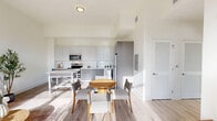 Located in Oakland Park, FL, this modern 1-bedroom, 2-bathroom residence offers a thoughtfully designed open-concept layout with clean lines and contemporary finishes. Light wood-look flooring runs throughout, complementing the bright, neutral color palette that enhances the sense of space.

The combined kitchen and living area serves as the heart of the home. The kitchen is outfitted with flat-panel gray cabinetry extending to the ceiling, stainless steel appliances including a range, microwave, dishwasher, and refrigerator, and a white quartz island that doubles as a dining surface. The living area benefits from dramatic floor-to-ceiling windows and a glass door that floods the space with natural light and provides direct access to an outdoor area with green views.

The bedroom is a serene retreat featuring tall windows with outdoor views, light wood flooring, and a walk-in closet equipped with wire shelving and hanging rods. Both bathrooms are finished with large-format tile flooring, floating gray vanities with white countertops, and clean, minimalist fixtures. Two hallways connect the spaces efficiently, contributing to a smooth and functional flow throughout. The overall ambiance is bright, airy, and modern — ideal for contemporary living.