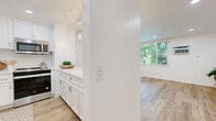 Located at 10720 Lakewood Blvd in Downey, CA, this well-appointed 1-bedroom, 1-bathroom residence offers a thoughtfully designed single-floor layout. Light wood-tone flooring flows consistently throughout, complementing a clean, modern aesthetic defined by crisp white walls and recessed lighting.

The open living area is generously sized, bathed in natural light from large windows that frame views of surrounding greenery. It connects seamlessly to the kitchen via a half-wall breakfast bar, making the layout ideal for both everyday living and entertaining. The kitchen features white shaker cabinetry with brushed gold hardware, marble-look quartz countertops, a white subway tile backsplash, and stainless steel appliances including a range and over-the-range microwave.

The bedroom is a comfortable, well-lit space with a ceiling fan, a window overlooking the outdoors, and warm wood flooring. A dedicated closet provides practical storage. The bathroom continues the gold accent theme with a wide white vanity, marble-look countertop, a large mirror, and elegant brass fixtures and lighting. A dedicated closet adds further convenience.

Overall, the unit presents a cohesive, modern design with bright, airy interiors and quality finishes throughout.