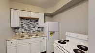 This single-story unit located on W Rich Street in Columbus, Ohio, offers a thoughtfully updated interior with modern finishes throughout. The kitchen is a standout feature, showcasing white shaker-style cabinetry, a granite-look countertop with a double-basin sink, and a striking mosaic tile backsplash with a gray-and-white pattern. White appliances, including a refrigerator and electric range, complete the functional cooking space, which also features wood-style plank flooring that extends throughout the unit.

The living area provides an open, comfortable layout with neutral gray walls, wood-style flooring, and an electrical panel conveniently integrated into the wall. The space flows naturally into adjoining rooms, creating a cohesive floor plan. Bedrooms are well-proportioned, featuring large windows that bring in natural light, ceiling fans, and generous closet space with built-in shelving and hanging rods.

The bathroom is clean and efficiently designed, offering a full tub and shower combination with a white surround, a white vanity, and coordinating fixtures. Consistent use of neutral tones and updated materials throughout the unit creates a fresh, move-in-ready atmosphere.