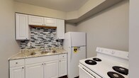 This single-story unit located on W Rich Street in Columbus, Ohio, offers a thoughtfully updated interior with modern finishes throughout. The kitchen is a standout feature, showcasing white shaker-style cabinetry, a granite-look countertop with a double-basin sink, and a striking mosaic tile backsplash with a gray-and-white pattern. White appliances, including a refrigerator and electric range, complete the functional cooking space, which also features wood-style plank flooring that extends throughout the unit.

The living area provides an open, comfortable layout with neutral gray walls, wood-style flooring, and an electrical panel conveniently integrated into the wall. The space flows naturally into adjoining rooms, creating a cohesive floor plan. Bedrooms are well-proportioned, featuring large windows that bring in natural light, ceiling fans, and generous closet space with built-in shelving and hanging rods.

The bathroom is clean and efficiently designed, offering a full tub and shower combination with a white surround, a white vanity, and coordinating fixtures. Consistent use of neutral tones and updated materials throughout the unit creates a fresh, move-in-ready atmosphere.