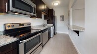 Located at 200 Rhode Island Avenue NE in Washington, DC, this single-floor residence offers a well-designed layout with clean finishes throughout. The living area features warm hardwood flooring and cool gray walls, creating a calm, neutral backdrop. Large double windows fitted with white blinds allow natural light to fill the space while providing views of the surrounding neighborhood streetscape.

The kitchen is thoughtfully appointed with dark espresso cabinetry, granite countertops, a white subway tile backsplash, and a full suite of stainless steel appliances including an electric range, microwave, dishwasher, and refrigerator. A convenient in-unit washer is also integrated into the kitchen area, adding everyday practicality. Light tile flooring completes the kitchen's clean, functional aesthetic.

The bathroom is finished with large-format light tile flooring, a white vanity with a dark granite countertop, a wall-mounted mirror, and a bathtub with a window above for natural ventilation. The entry area continues the hardwood flooring theme, with a crisp white door and clean wall finishes that carry consistently throughout the unit. The overall ambiance is modern, understated, and move-in ready.