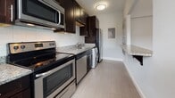 Located at 200 Rhode Island Avenue NE in Washington, DC, this single-floor residence offers a well-designed layout with clean finishes throughout. The living area features warm hardwood flooring and cool gray walls, creating a calm, neutral backdrop. Large double windows fitted with white blinds allow natural light to fill the space while providing views of the surrounding neighborhood streetscape.

The kitchen is thoughtfully appointed with dark espresso cabinetry, granite countertops, a white subway tile backsplash, and a full suite of stainless steel appliances including an electric range, microwave, dishwasher, and refrigerator. A convenient in-unit washer is also integrated into the kitchen area, adding everyday practicality. Light tile flooring completes the kitchen's clean, functional aesthetic.

The bathroom is finished with large-format light tile flooring, a white vanity with a dark granite countertop, a wall-mounted mirror, and a bathtub with a window above for natural ventilation. The entry area continues the hardwood flooring theme, with a crisp white door and clean wall finishes that carry consistently throughout the unit. The overall ambiance is modern, understated, and move-in ready.