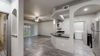 Located at 11212 Westpark Dr in Houston, Texas, this 2-bedroom, 3-bathroom single-floor residence offers a well-organized layout with consistent wood-look flooring and a neutral color palette throughout. The open living area is anchored by a ceiling fan and large sliding glass doors fitted with vertical blinds, flooding the space with natural light and providing views of the surrounding greenery. Crown molding adds a refined architectural touch to the living room.

The kitchen is defined by a peninsula featuring dark granite countertops and an undermount sink, with white shaker-style cabinetry, open shelving, and a full suite of stainless steel appliances including a refrigerator, range, and microwave. A dedicated in-unit laundry area includes a full-size washer and dryer with built-in shelving for additional storage.

Both bedrooms are generously proportioned, each equipped with a ceiling fan and access to natural light through windows or sliding doors. The primary bedroom connects to a hallway leading to a well-appointed bathroom with a dual-sink vanity and dark cabinetry. One bathroom features a soaking tub with tiled surround. Two closets provide practical storage solutions. The overall design is clean, modern, and functional.
