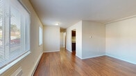 This one-bedroom, one-bathroom unit at 10500 Hackberry Dr in Saint Louis, MO offers a practical and well-organized layout across a single floor. The living room serves as the welcoming centerpiece of the space, featuring rich hardwood-style flooring, neutral beige walls, and two windows that allow generous natural light to fill the room. A wall-unit air conditioner and baseboard heating ensure year-round comfort. The kitchen is situated adjacent to the living area and includes laminate countertops, ample cabinetry with dark wood-toned finishes, a white electric range with a tiled backsplash, and hardwood-style flooring that continues the cohesive aesthetic. The bedroom offers a quieter retreat, carpeted for warmth and comfort, with a large window overlooking the surrounding neighborhood and a baseboard heater. A set of sliding double-panel closet doors provides practical storage. The bathroom is clean and functional, featuring a full tub-and-shower combination with tiled surround, a toilet, and a vanity with a white cabinet base, all set on hardwood-style flooring. Throughout the unit, the neutral color palette and consistent finishes create a simple, cohesive ambiance well-suited for comfortable everyday living.