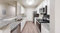 Located at 1200 Virginia Center Pkwy in Glen Allen, Virginia, this single-floor unit offers a clean, move-in-ready layout designed for comfortable everyday living. The open-concept living area is generously proportioned, finished with plush wall-to-wall carpeting and neutral warm-toned walls that create a bright, welcoming atmosphere. A ceiling fan provides added comfort, while a large window allows natural light to fill the space and offers pleasant views of the surrounding greenery. The galley-style kitchen is a functional highlight, featuring granite countertops, crisp white cabinetry, wood-look plank flooring, and a full suite of stainless steel appliances including a refrigerator, electric range, microwave, and dishwasher. A double-basin sink with a modern faucet completes the well-equipped space. The bedroom is comfortably sized, carpeted, and benefits from dual windows fitted with blinds that invite natural light while maintaining privacy. The bathroom is thoughtfully finished with a granite-topped vanity, white cabinetry, a large mirror with overhead lighting, and a full tub and shower combination with tiled surround, all set on wood-look flooring. Throughout the unit, consistent finishes and a neutral color palette contribute to a cohesive and polished overall aesthetic.