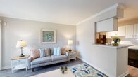 Located near Space Center Houston in Houston, TX, this one-bedroom, one-bathroom residence offers a thoughtfully designed single-level layout with a coastal-inspired aesthetic. The entryway welcomes you with wood-look flooring, crown molding, and neutral tones that carry throughout the main living areas. The living room is bright and inviting, featuring large sliding glass doors that allow generous natural light to fill the space, crown molding details, and a pass-through window connecting to the kitchen. The adjacent dining area accommodates a full dining table and is accented by a built-in shelving unit, adding both function and character. The galley-style kitchen is well-equipped with granite countertops, white cabinetry, black appliances including a range, microwave, refrigerator, and dishwasher, plus track lighting and wood-look flooring. The bedroom offers plush carpet flooring, a ceiling fan, a window with natural light, and a dedicated closet. The full bathroom features a granite-topped vanity with white cabinetry, wood-look tile flooring, and a tub/shower combination with classic white tile surround. Overall, the space presents a clean, cohesive design with a relaxed coastal palette of blues, greens, and soft neutrals.