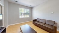 Located at 18490 Dunn Rd in South Bend, Indiana, this single-floor residence offers three bedrooms and three full bathrooms in a thoughtfully arranged layout. The open-concept kitchen is a functional highlight, featuring stainless steel appliances — including a refrigerator, range, and over-the-range microwave — dark espresso cabinetry, granite-style countertops, and a breakfast bar with seating for multiple guests. Light wood flooring flows through the kitchen and living areas, lending warmth and visual continuity throughout. The living room is bright and welcoming, with a large window that invites natural light and offers views of the surrounding greenery. Each bedroom is carpeted with a distinctive geometric-patterned rug, providing a comfortable and stylish feel. The primary bedroom offers a generous footprint with closet access, while the additional bedrooms are well-sized and versatile, each suited for sleeping or study. All three bathrooms maintain a consistent, clean aesthetic with dark wood vanities, white countertops, large mirrors, and tile flooring. Two bathrooms include a full tub-shower combination. The overall design is modern and neutral, with light gray walls throughout creating a cohesive, move-in-ready atmosphere.