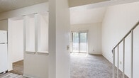 Located at 2604 S Topeka St in Wichita, Kansas, this single-floor unit presents a functional and well-organized layout. The living area is a standout feature, characterized by dramatic vaulted ceilings that create a sense of openness and volume. Vertical blinds cover a full-width sliding glass door that floods the space with natural light and provides outdoor access. Neutral-toned carpet runs throughout the living and bedroom areas, contributing to a cohesive, understated aesthetic.

The kitchen is equipped with warm oak cabinetry both above and below the countertops, a double stainless steel sink, light gray laminate countertops, and a built-in dishwasher, offering practical functionality. The bathroom features a full tub-shower combination, a wood-trimmed vanity with a white countertop, and a large mirror that enhances the sense of space.

The bedrooms vary in character: one features soaring ceilings with high transom windows, textured wainscoting, louvered bifold closet doors, and an additional walk-in closet, while another offers a standard layout with a window providing natural light and a textured ceiling. Overall, the space maintains a clean, neutral palette throughout.