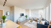 Located at 3200 Northwoods Rd in Saukville, Wisconsin, this efficiently designed single-floor unit offers a bright, modern living experience. The open-concept layout seamlessly connects the kitchen and living room, maximizing the use of the available space while maintaining a clean, airy feel throughout.

The kitchen is well-appointed with white shaker-style cabinetry, stainless steel appliances including a range, microwave, and refrigerator, and a light countertop island with seating for multiple guests. A sleek track light fixture overhead adds focused illumination, making the kitchen both functional and stylish.

The living area benefits from large windows that invite an abundance of natural light, creating a warm and welcoming atmosphere. Light-toned hardwood-style flooring runs continuously throughout the space, contributing to a cohesive and contemporary aesthetic. Neutral warm-white walls provide a versatile backdrop throughout.

The bathroom features a walk-in glass-enclosed shower with a sliding door, light wood-style flooring, and clean white walls, offering a modern and practical design.

Overall, the unit presents a thoughtfully planned layout with modern finishes, ample natural light, and efficient use of space, making it a comfortable and functional home in Saukville, WI.