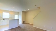 Located at 3900 Suffolk Dr in Dublin, Ohio, this two-story home offers a clean, functional layout across two well-organized floors. The kitchen is thoughtfully designed with ample white cabinetry extending to the ceiling, generous counter space, and a full suite of white appliances including a refrigerator, electric range, built-in microwave, and dishwasher. A double basin sink sits beneath a window that brings in natural light, keeping the workspace bright and welcoming. Recessed lighting and light-toned countertops contribute to the kitchen's crisp, airy atmosphere. The adjacent living area is open and inviting, featuring plush wall-to-wall carpeting and recessed ceiling lights that provide consistent, even illumination throughout the space. Neutral-toned walls offer a versatile backdrop suited to a variety of interior styles. A staircase with white railings leads to the upper floor, adding a sense of vertical openness to the main level. A front entry door with sidelights allows additional natural light into the living area, connecting the interior to the outdoors. Together, these spaces form a cohesive and comfortable home well-suited for everyday living in the Dublin community.